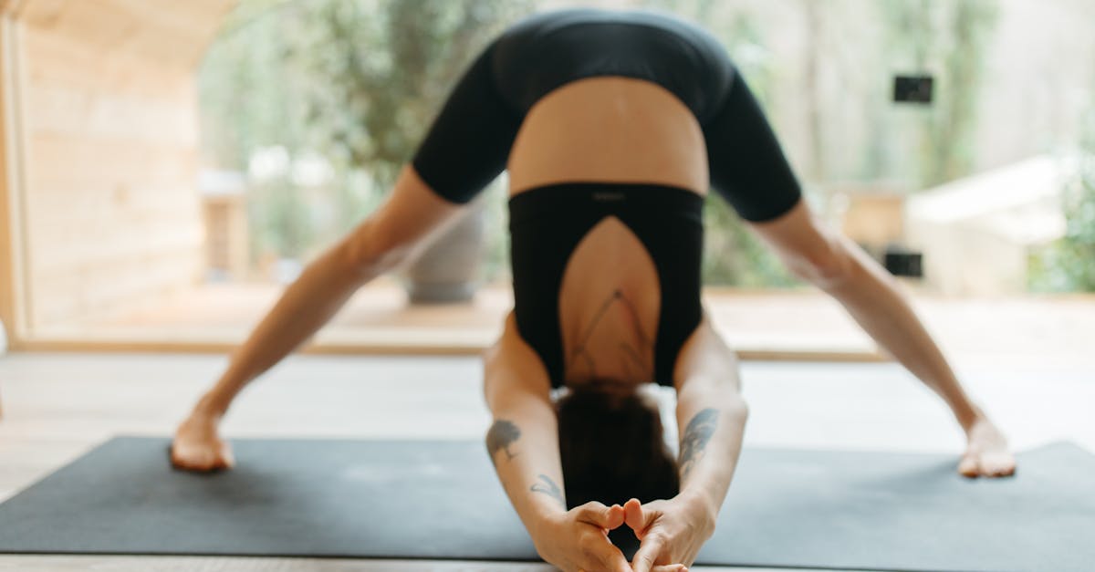 A woman practicing yoga indoors, demonstrating flexibility and concentration on a yoga mat.